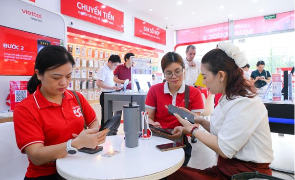 Khách hàng và nhân viên Viettel áo đỏ đang dùng điện thoại đen tại cửa hàng Viettel.