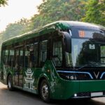 Xe buýt điện VinFast EB8 màu xanh Hanoibus với họa tiết chim hòa bình và Khuê Văn Các chạy trên phố Hà Nội